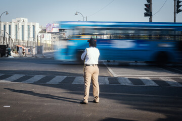 A female traffic officer controlling traffic on a busy road