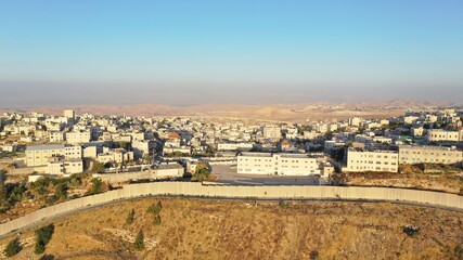 Obraz premium Anata Refugees Camp with security wall Near Pisgat zeev, Israel, Aerial Drone view, Judea desert in Background, July, 2020, Sunset 