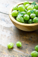 Sweet fresh gooseberry berry in a bowl on wood background.