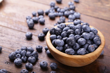 Freshly picked blueberries in wooden bowl on a wooden  table.