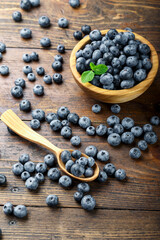 Freshly picked blueberries in wooden bowl on a wooden  table. Healthy fruits.