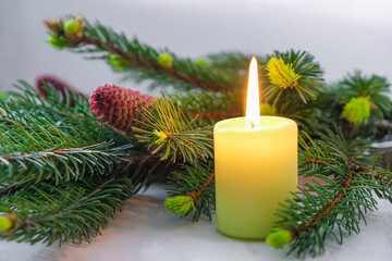 Christmas candle flame and spruce branch with red cone on a gray background. Quarantine Christmas concept.  Sad Christmas concept.