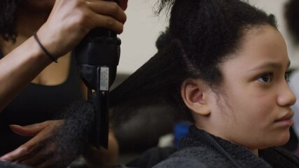 Young child of mixed ethnicity having her hair blow-dried 