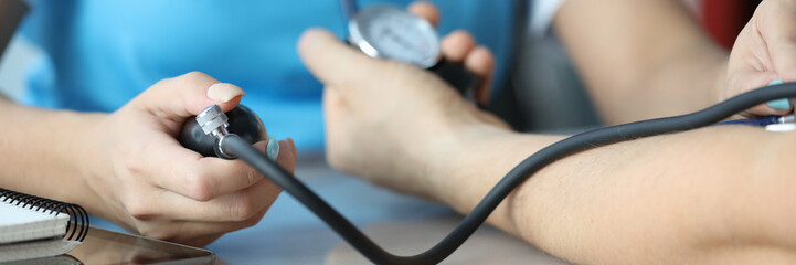 Close-up of female doctor in uniform examining blood pressure holding part of equipment. Patient at medical appointment. Modern medicine and health checkup concept