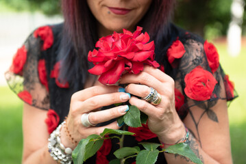 Fototapeta na wymiar Woman smelling red roses in garden.