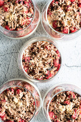Top view on cup with pudding with fresh organic raspberries biscuits and chocolate - Bright filter image on homemade sweet desert in glasses - Fresh summer concept on marble stone background