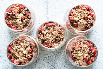 Top view on cup with pudding with fresh organic raspberries biscuits and chocolate - Bright filter image on homemade sweet desert in glasses - Fresh summer concept on marble stone background