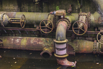 Old, rusty pipeline and a layer of water, clearly abandoned.