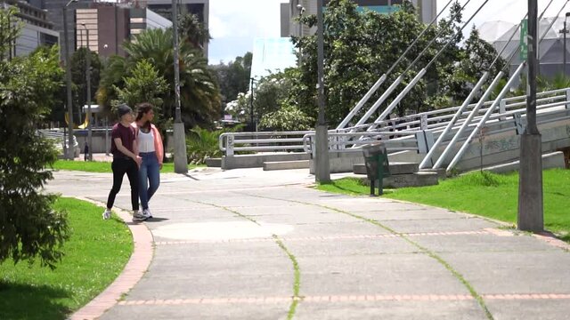 Novios jovenes caminan en el parque en un d&iacute;a soleado mientras observan la naturaleza y conversan. Amigos disfrutando de un momento juntos. 
