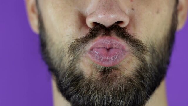 Close up portrait of a young bearded guy who sends an air kiss. Handsome bearded man looks at the camera and sends an air kiss .