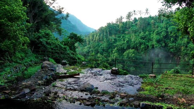 Waterfall and in eastern tropical forest. Camera is moving from the dam to the waterfall and flying above, Drone aerial, slow motion.