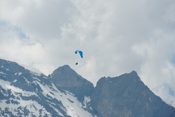 A paraglider gliding over mountain peaks in region Engelberg canton Obwalden in Switzerland in the...