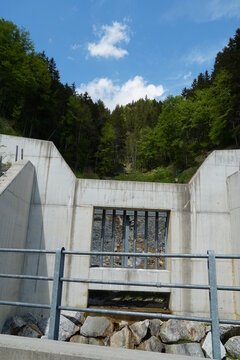 Concrete barrier of a forest brook to prevent stones falling into the valley with stron stream of water coming from melting snow in the Alps, Engelberg region canton Obwalden in Switzerland.