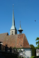 Fototapeta na wymiar Zug / Switzerland 05 09 2020; St. Oswald's Church Tower built in Gothic style with the background of blue sky.