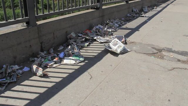 Newspaper litter on an sidewalk overpass in urban Toronto, Canada. Shot on the south end of Dufferin in the Parkdale neighborhood.