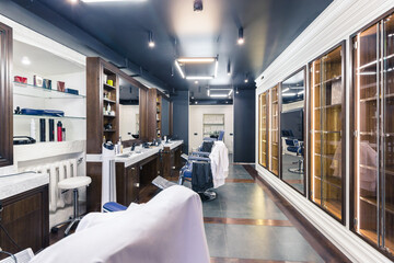 luxury barber shop interior, blue expensive furniture, wood trim, fashionable black ceiling, white robes on the backs of armchairs