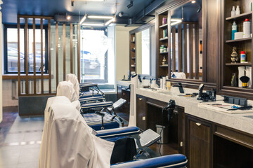 luxury barber shop interior, blue expensive furniture, wood trim, fashionable black ceiling, white robes on the backs of armchairs