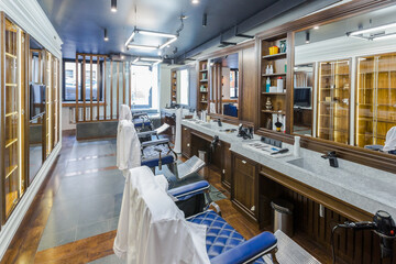 luxury barber shop interior, blue expensive furniture, wood trim, fashionable black ceiling, white robes on the backs of armchairs
