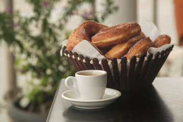 doughnuts in sugar on a plate and a Cup of espresso coffee, close-up