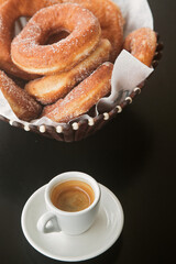 doughnuts in sugar on a plate and a Cup of espresso coffee, close-up
