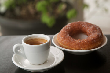 doughnut in sugar on a plate and a Cup of espresso coffee, close-up