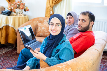 Happy arabic family sitting on sofa and using technology