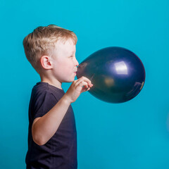 Cute boy blond European in a black t-shirt on a blue background in the Studio. A surprised...