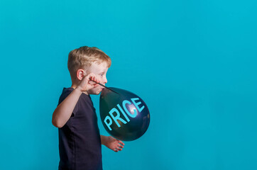 Cute funny Baby inflates and bursts a balloon with the text price on black Friday. Boy on a blue...