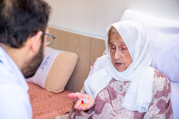 Old woman and her doctor having conversation and explanation therapy details and medication dosage during house call medical check-up