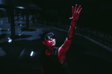 Cyberpunk. Tattooed man in futuristic glasses pulls his arm. The concept of the future of mankind.