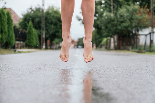 Feet Of A Woman Jumping Over A Puddle In The Rain