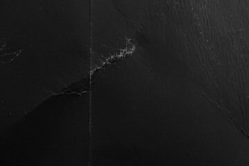 Old black paper with creases and scratches. Worn packaging material. Abstract background. Macro shot