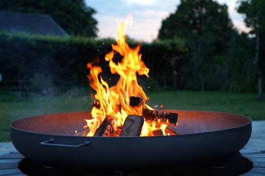 Iron fire pit and burning fire in a garden .  Campfire ,  close up image .
