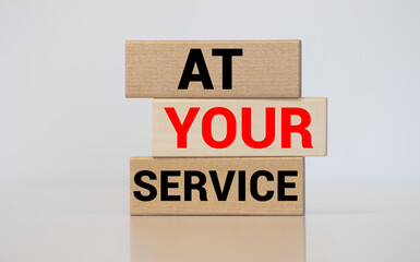 At Your Service written on a wooden cube in front of a telephone conceptual of help, client services, assistance, expertise and consultancy.