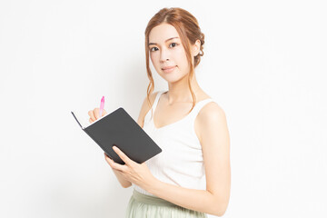 手帳にメモを書く若い女性