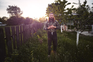Young Caucasian rural man in his backyard at sunset.