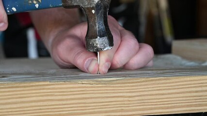 Slow motion hammering in a finishing nail into a pine board - Powered by Adobe