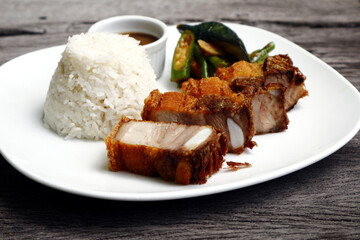 Filipino food called Lechon Kawali or crispy deep fried pork with rice and vegetables on a plate