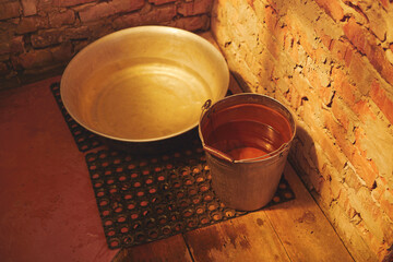 Close-up of an iron bucket and an aluminum bowl in a summer shower.