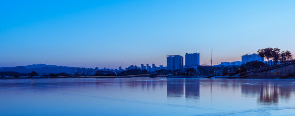 Fototapeta premium Frozen lake and skyline at blue hour