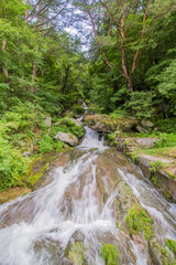 Fototapeta na wymiar Beautiful natural waterfall cascading down mountain hillside.