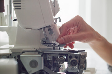 Woman tailor at a sewing machine. Close-up of hands.