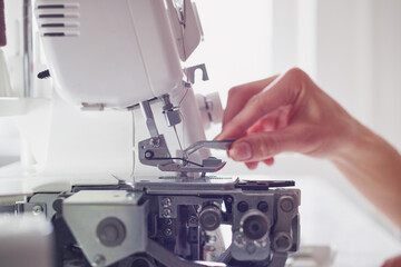 Woman tailor at a sewing machine. Close-up of hands.