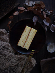 A Slice of Cake on Wooden Table. Autumn Dessert. Vanilla Chiffon Cake on Dark Background with Copy Space. Dark Moody Dessert Photography. Layer Cake Flatlay.