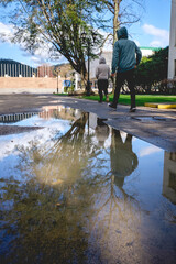 2 guys with hoodies walking in front a water pond with reflections at the campus of the University of Concepción