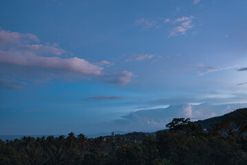 Colorful sunset over forest, village, sea and mountains on a tropical island. View from the top.