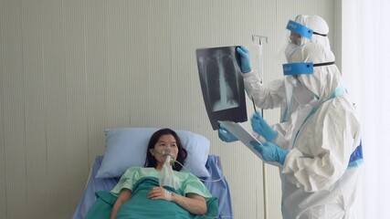 doctor and nurse in personal protective equipment or ppe showing chest film to the asian patient who is infected with covid-19 or coronavirus. healthcare and medical concept - Powered by Adobe