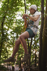 Naklejka na ściany i meble Young caucasian slackliner man doing slackline in the forest on a summer day.