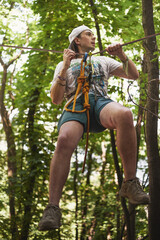 Young caucasian slackliner man doing slackline in the forest on a summer day.