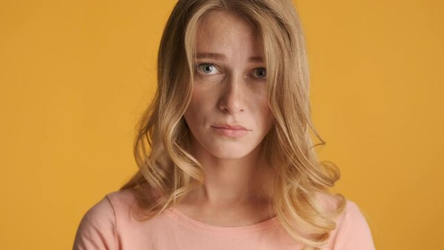 Beautiful upset blond girl guilty looking in camera over colorful background. Guilty face expression